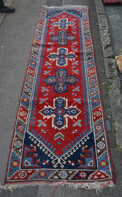 Appraisal: An Afghan red ground runnerwith four star shaped medallions within