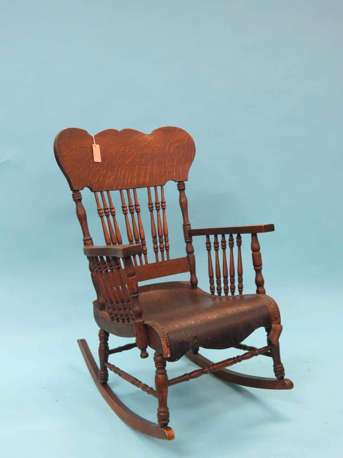 Appraisal: A dark oak rocking armchair with spindle back as viewed