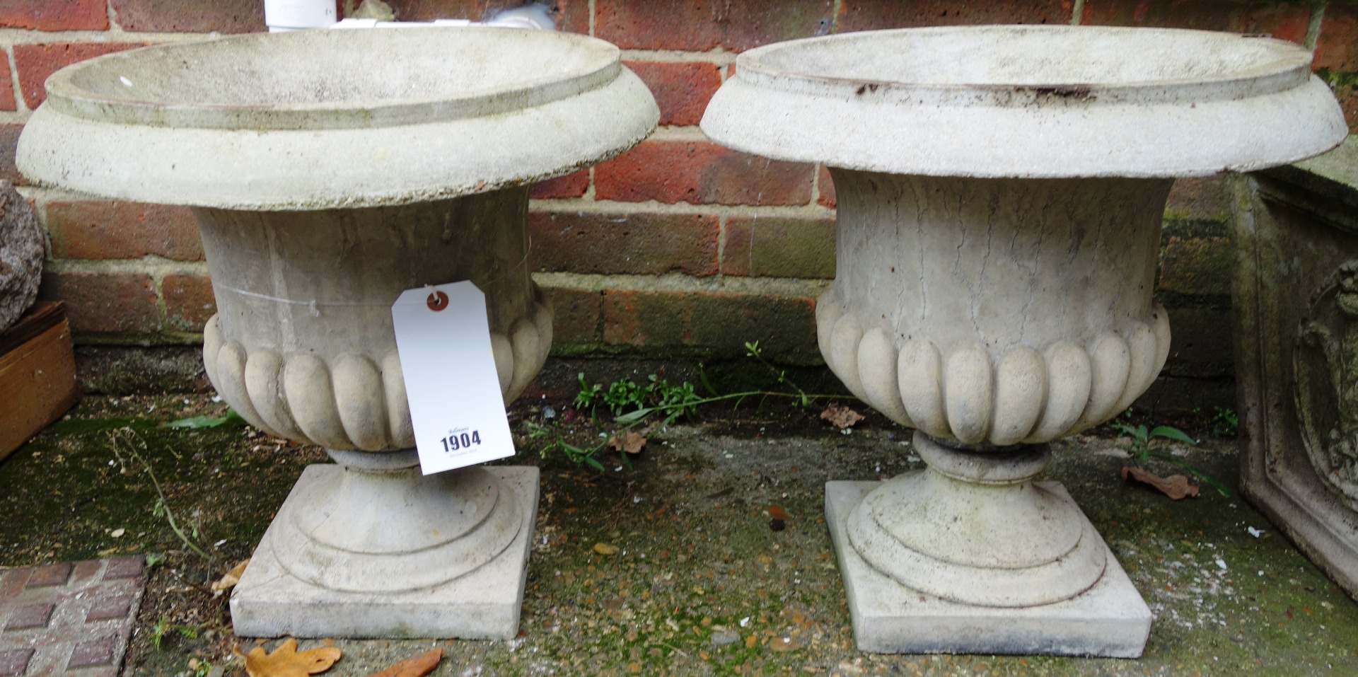 Appraisal: A pair of composition stone campana urns on turned socles