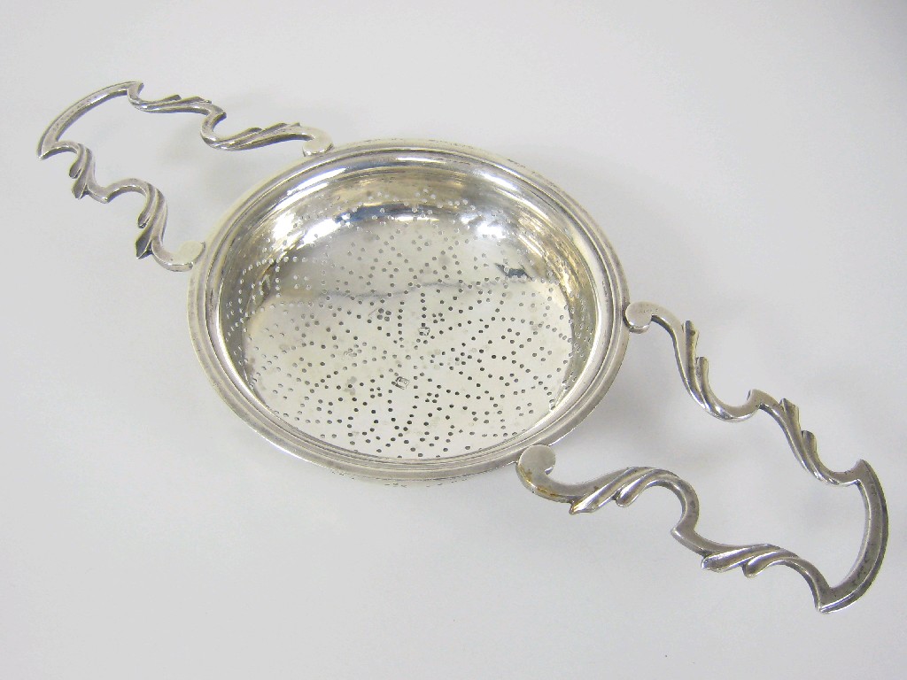 Appraisal: A George III Lemon Strainer with two leafage scroll handles