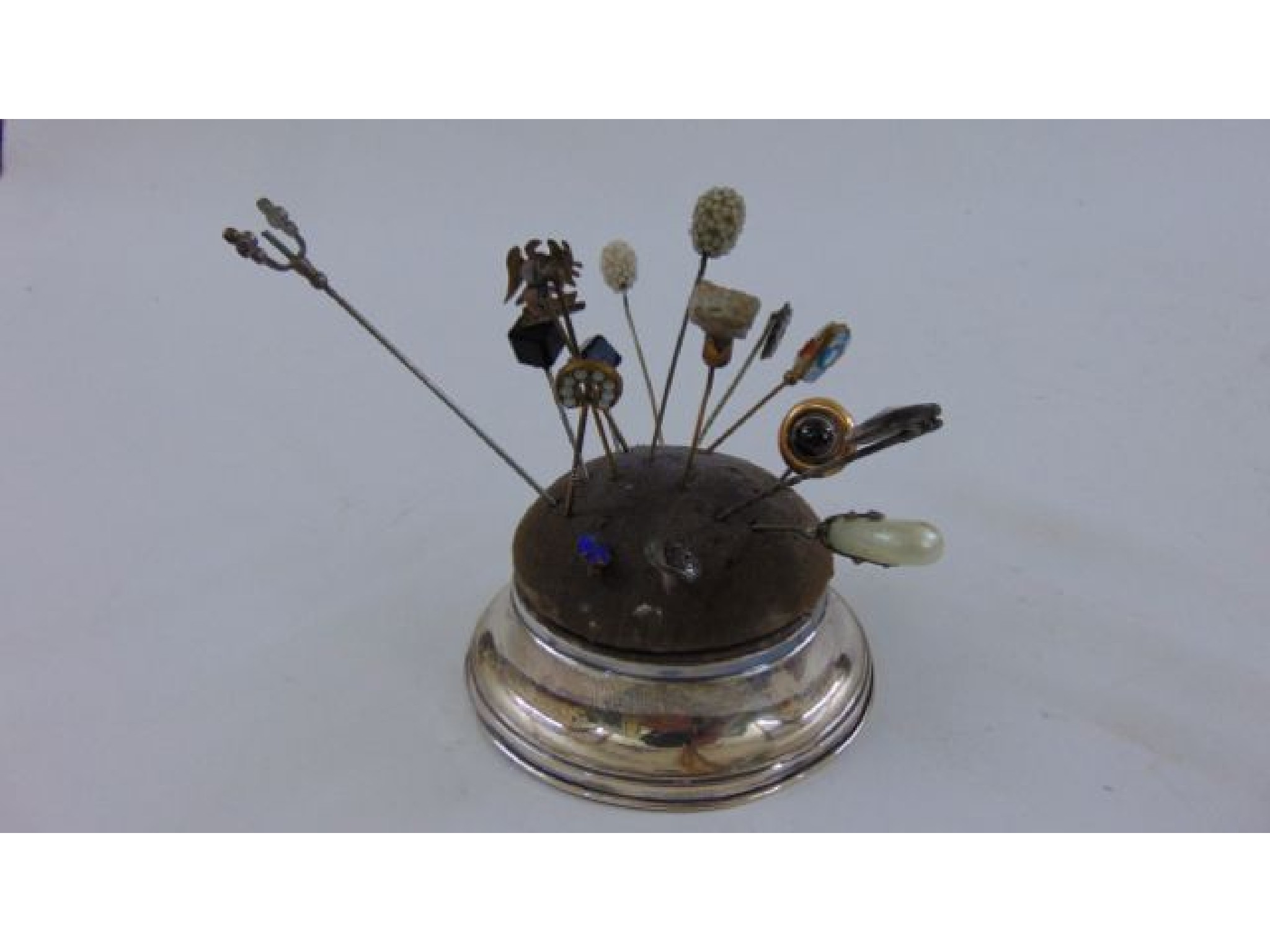 Appraisal: A circular silver hat pin holder containing a small selection