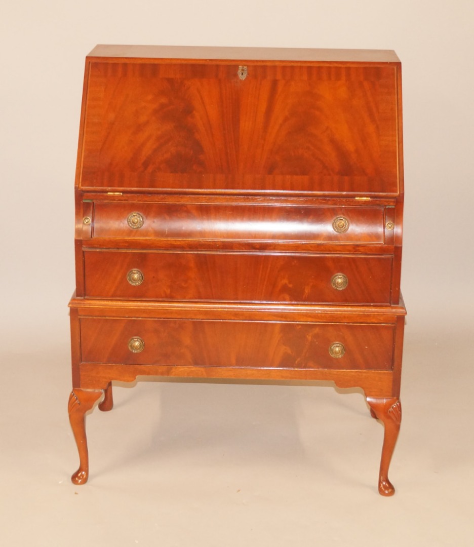 Appraisal: A reproduction flamed mahogany bureau the fall enclosing a fitted