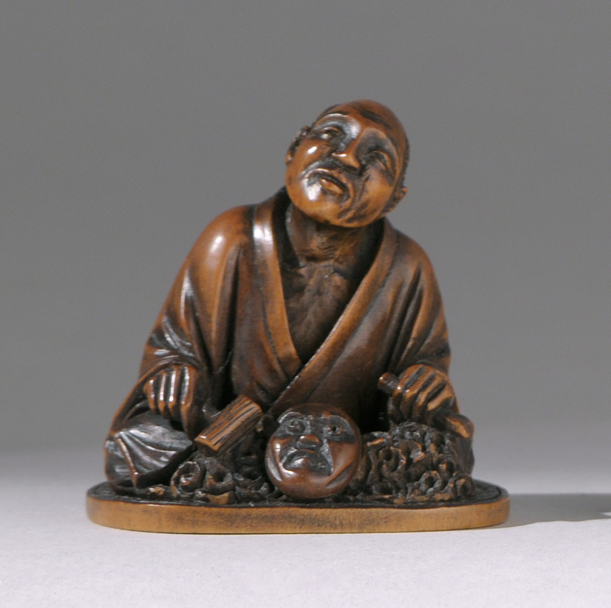 Appraisal: WOOD NETSUKE Meiji PeriodBy Toshimitsu Depicting a seated mask carver