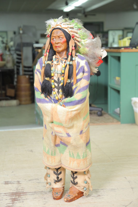 Appraisal: LARGE SKOOKUM CHIEF Wearing beaded moccassins and a large feather