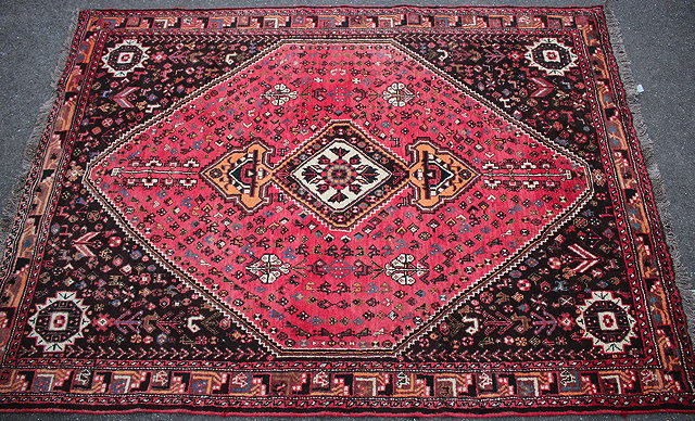 Appraisal: AN ORIENTAL RED GROUND RUG with central diamond motif the