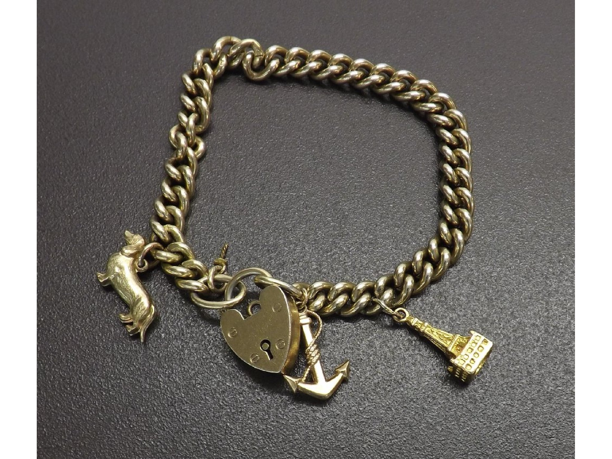 Appraisal: Silver-gilt curb link charm bracelet with padlock clasp and three