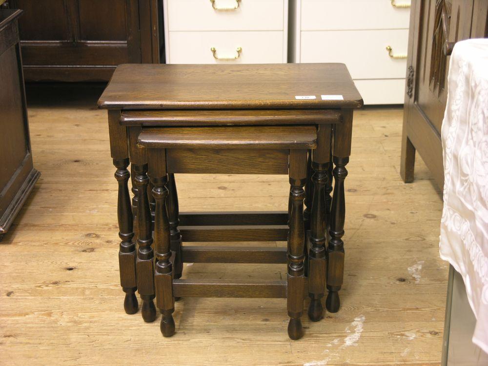 Appraisal: A solid dark oak nest of three tables on baluster