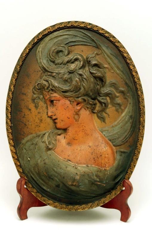 Appraisal: A framed metal low relief plaque of a woman with