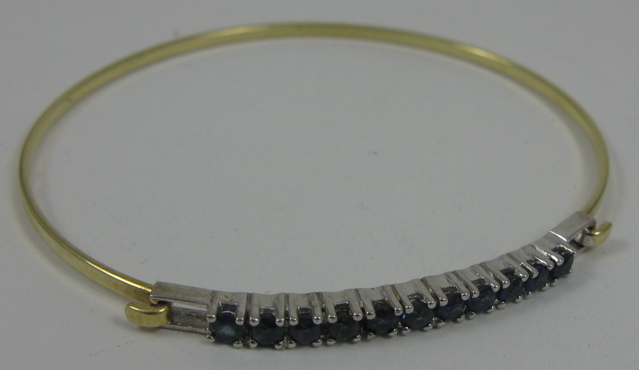 Appraisal: SAPPHIRE AND FOURTEEN KARAT GOLD BANGLE The yellow and white