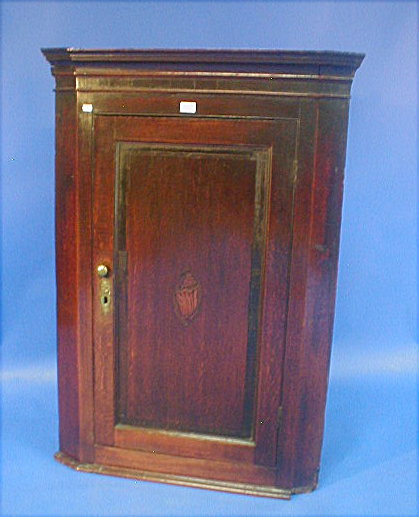 Appraisal: A George III oak hanging corner cupboard with moulded cornice