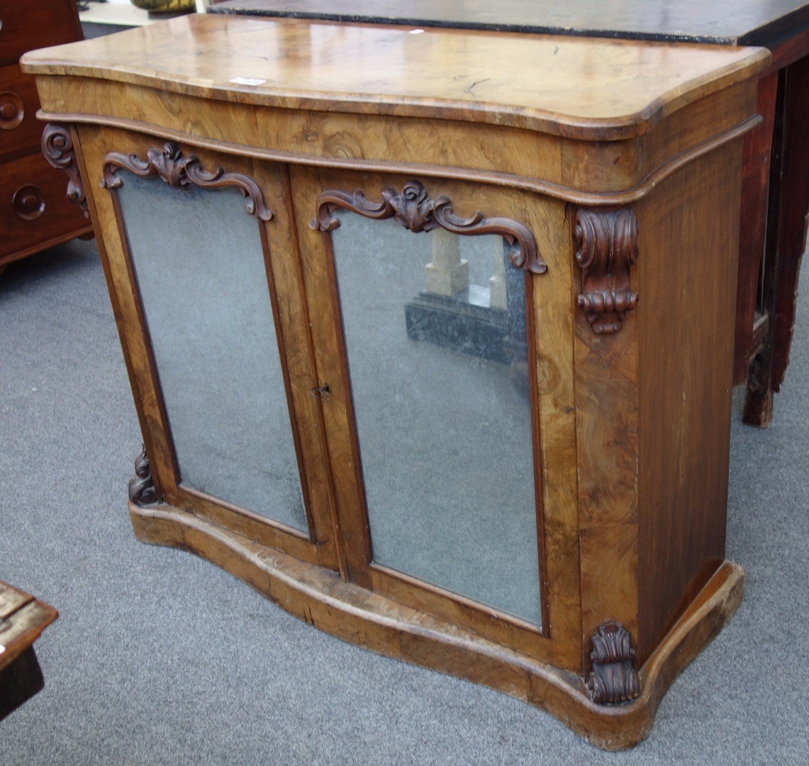 Appraisal: A Victorian figured walnut side cabinet with serpentine top over