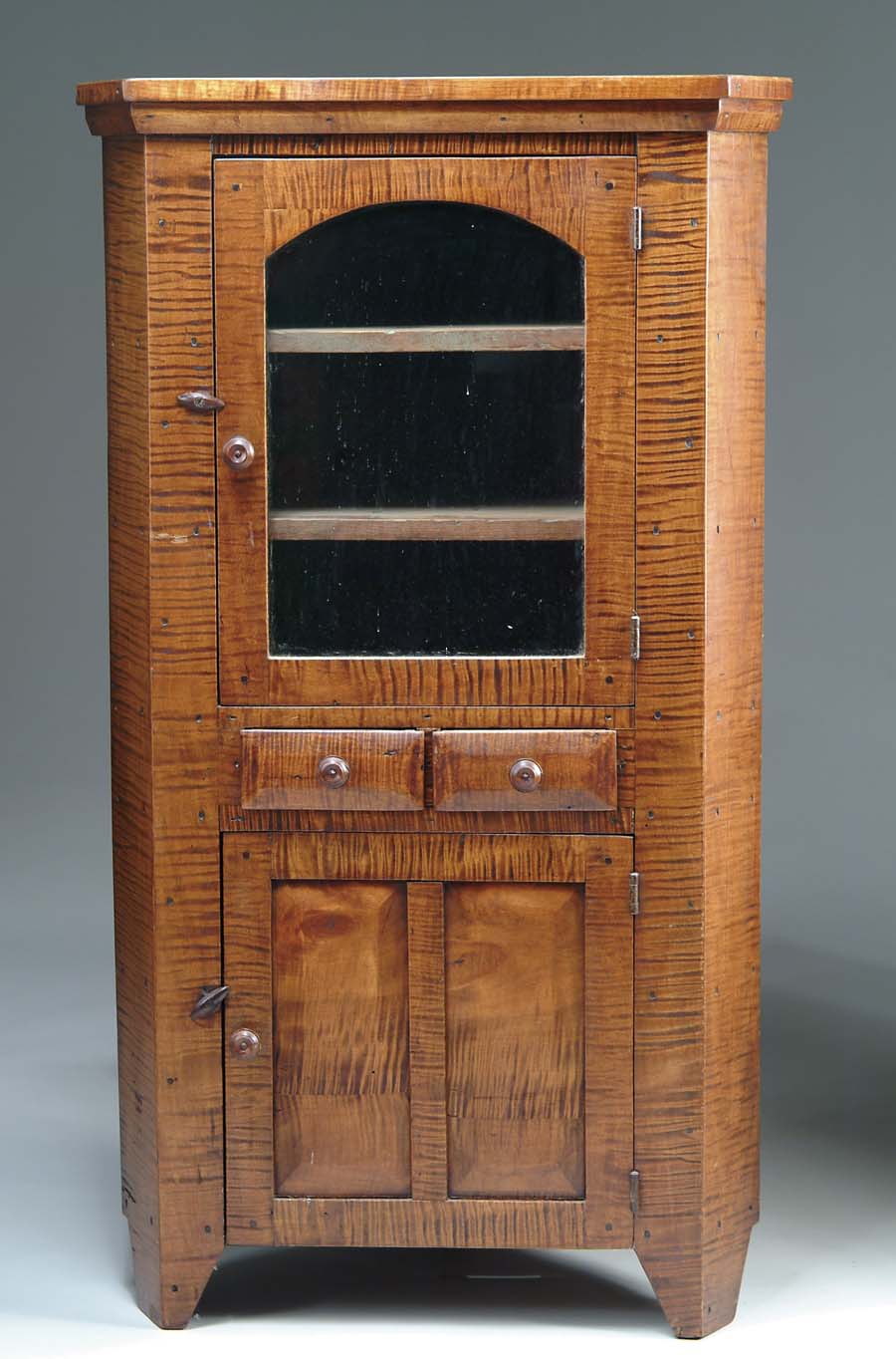 Appraisal: TIGER MAPLE CORNER CUPBOARD Diminutive cupboard with tombstone glazed upper