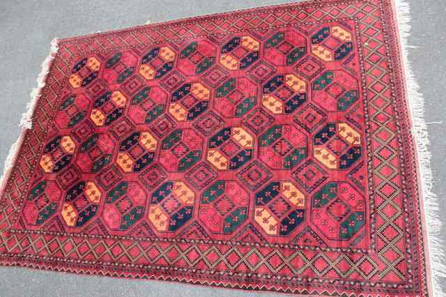 Appraisal: AN AFGHAN WINE GROUND RUG decorated with four rows of