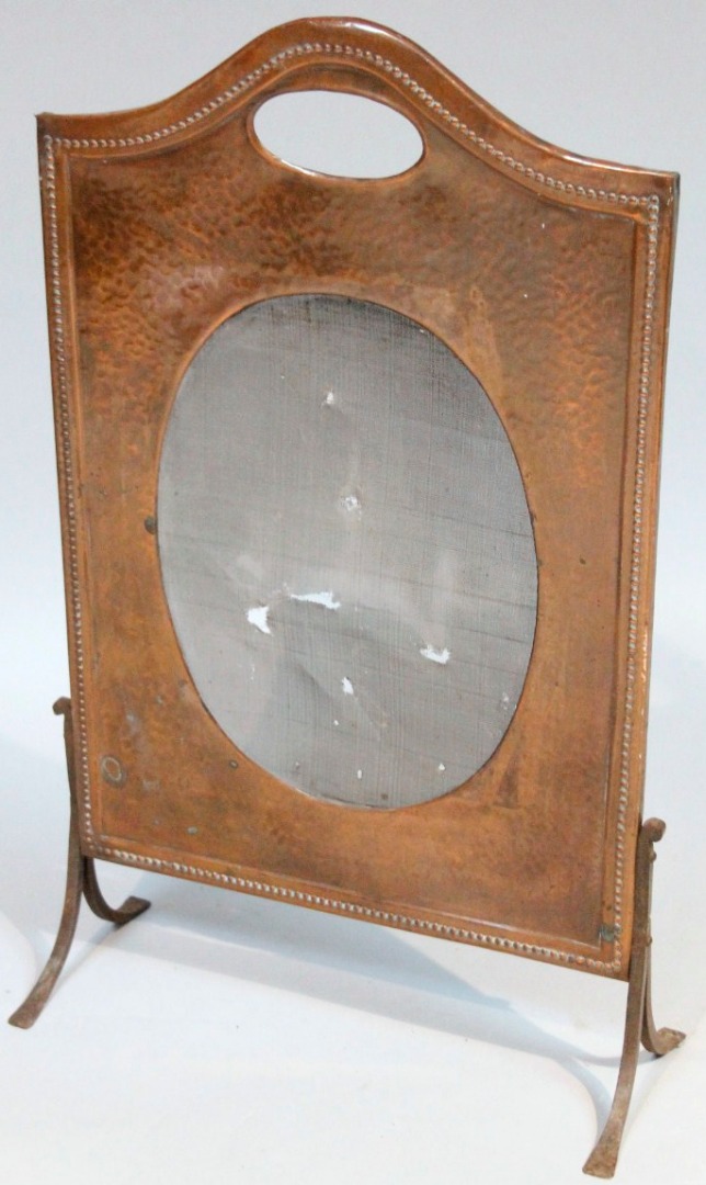 Appraisal: An Edwardian hammered copper fire screen with oval mirror and