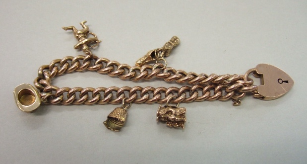 Appraisal: A gold curb link charm bracelet fitted with five charms