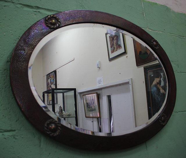 Appraisal: AN ARTS AND CRAFTS HAMMERED COPPER OVAL WALL MIRROR the