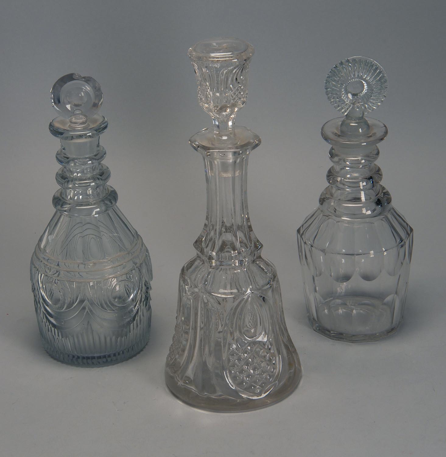 Appraisal: THREE CLEAR GLASS DECANTERS with stoppers Two are three-ring one