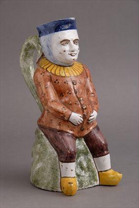 Appraisal: CONTINENTAL FAIENCE FIGURAL JUG Modeled as a seated pot-bellied man