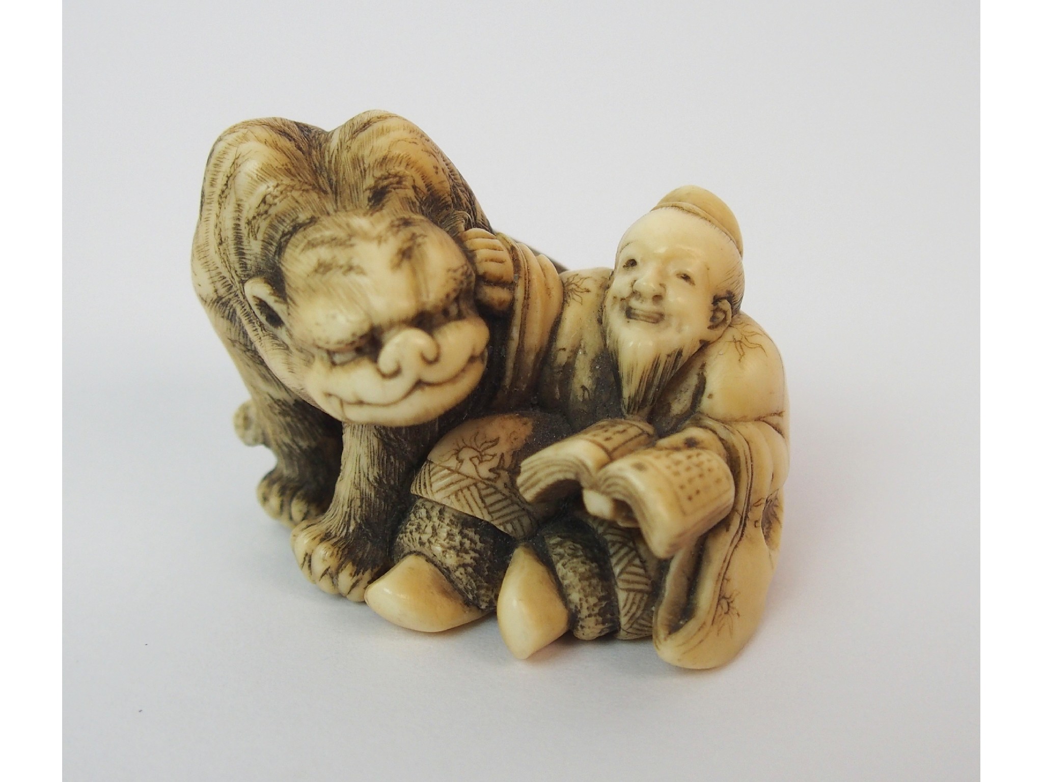 Appraisal: A Japanese ivory netsukeof a grotesque animal and scholar seated