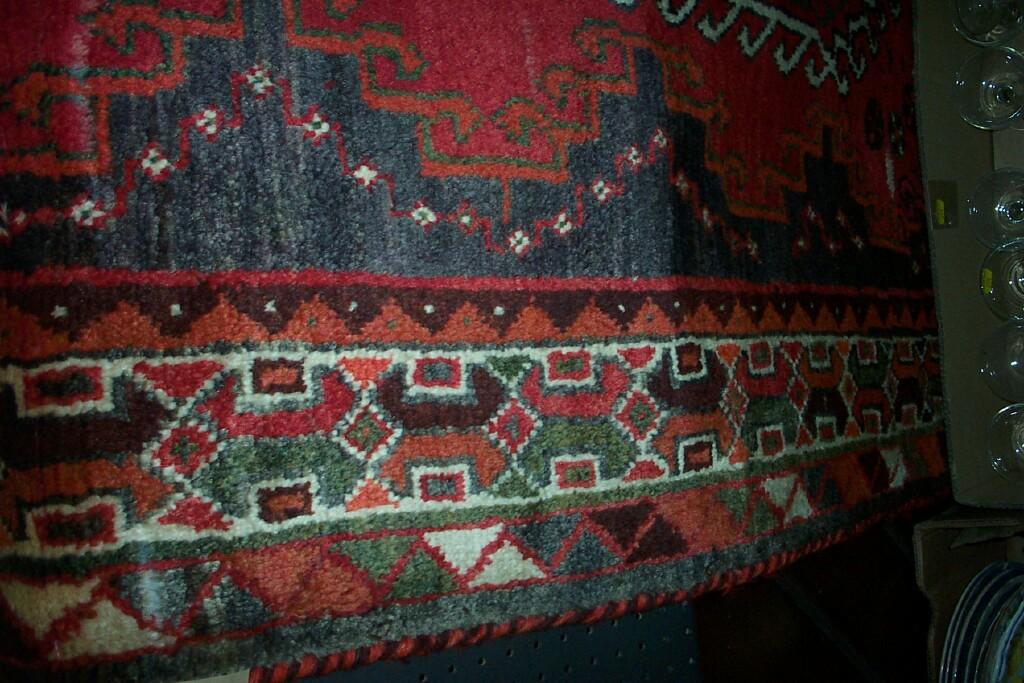 Appraisal: A red ground Eastern wool rug with geometric and hooked