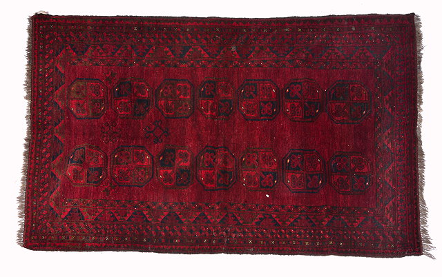 Appraisal: AN AFGHAN DARK RED GROUND RUG with two rows of