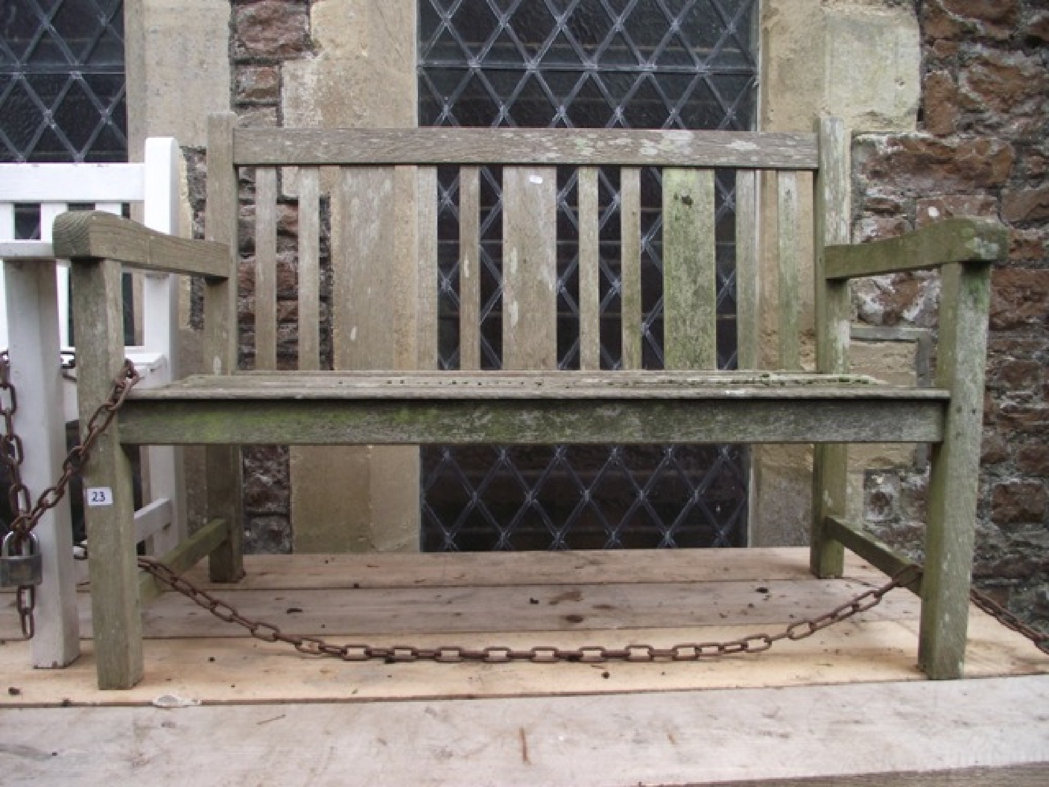 Appraisal: A weathered teak two seat garden bench with slatted seat