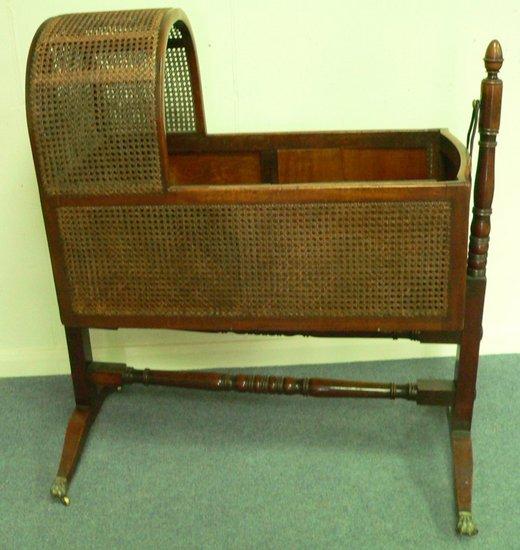 Appraisal: A th Century cradle with caned surround raised on turned