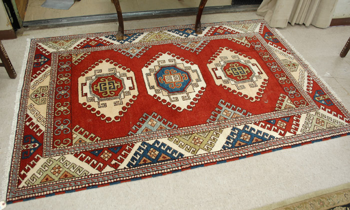 Appraisal: HAND KNOTTED ORIENTAL CARPET Indo-Kazak tribal three geometric medallion design