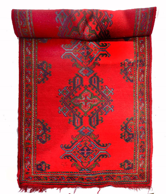 Appraisal: A TURKEY RED GROUND RUNNER with five central stylised medallions