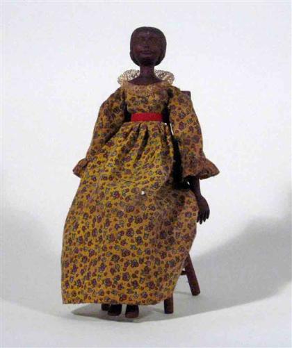 Appraisal: Carved doll with chair th century African American doll wearing