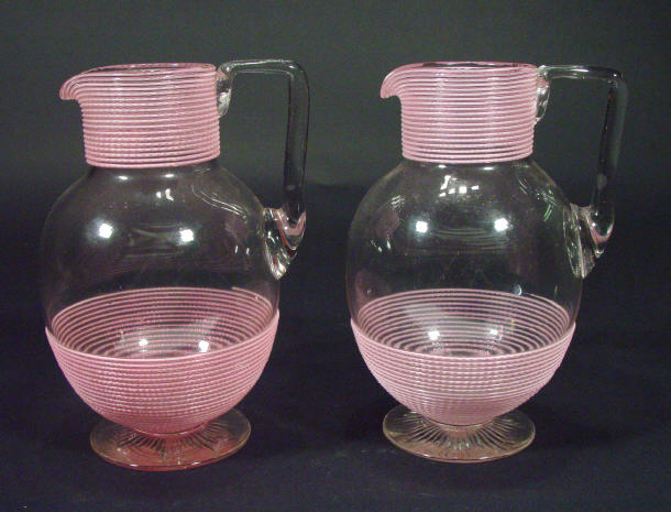 Appraisal: Two Victorian clear glass ewers with pink enamelled ribbing on