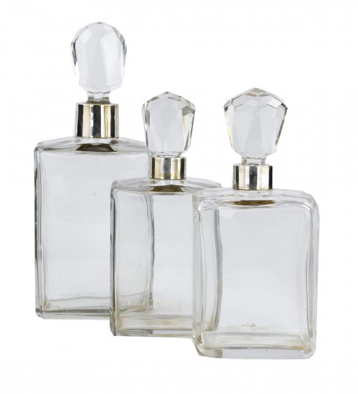 Appraisal: THREE SIMILAR SILVER-MOUNTED GLASS SPIRIT DECANTERS AND STOPPERS the largest