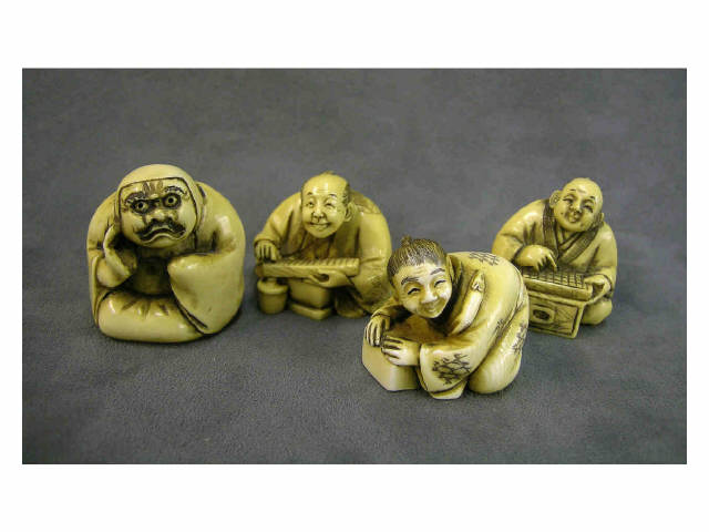 Appraisal: Four seated lightly stained netsuke including man in mask holding