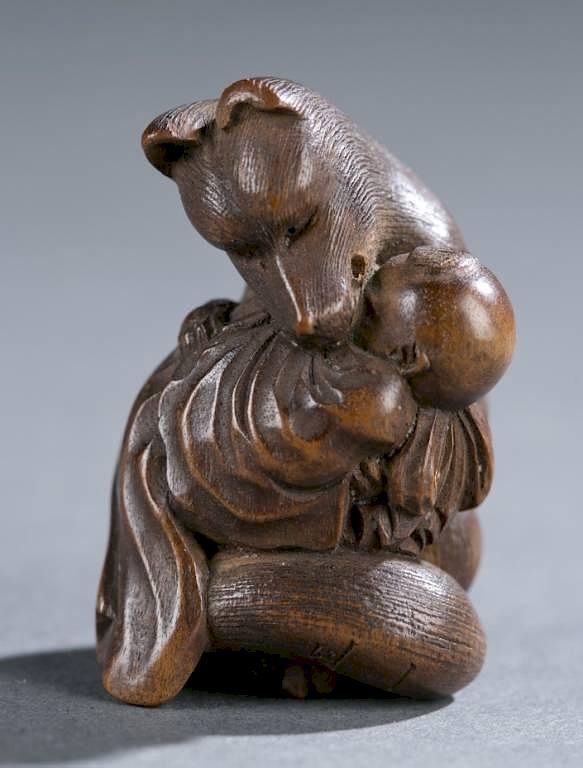 Appraisal: Japanese wood carving of fox holding baby A Japanese wood