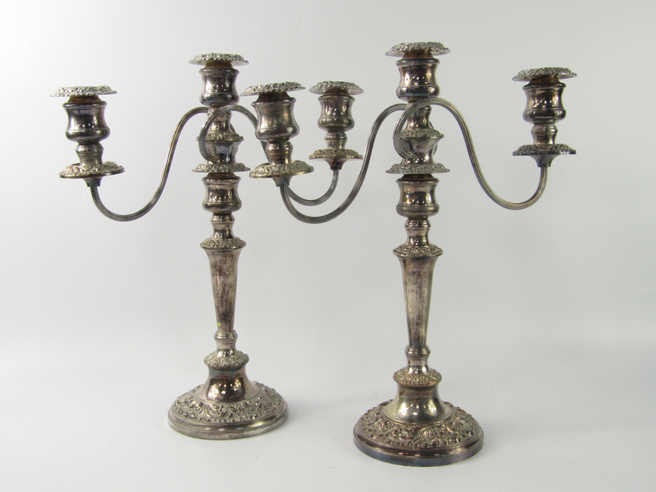 Appraisal: A pair of plated three branch candelabra with embossed foliate