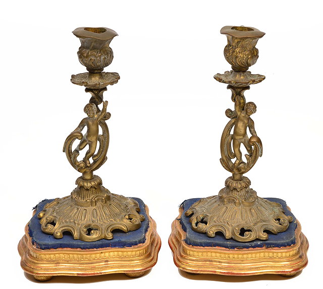 Appraisal: A PAIR OF CONTINENTAL CAST BRASS CANDLESTICKS with putti supports