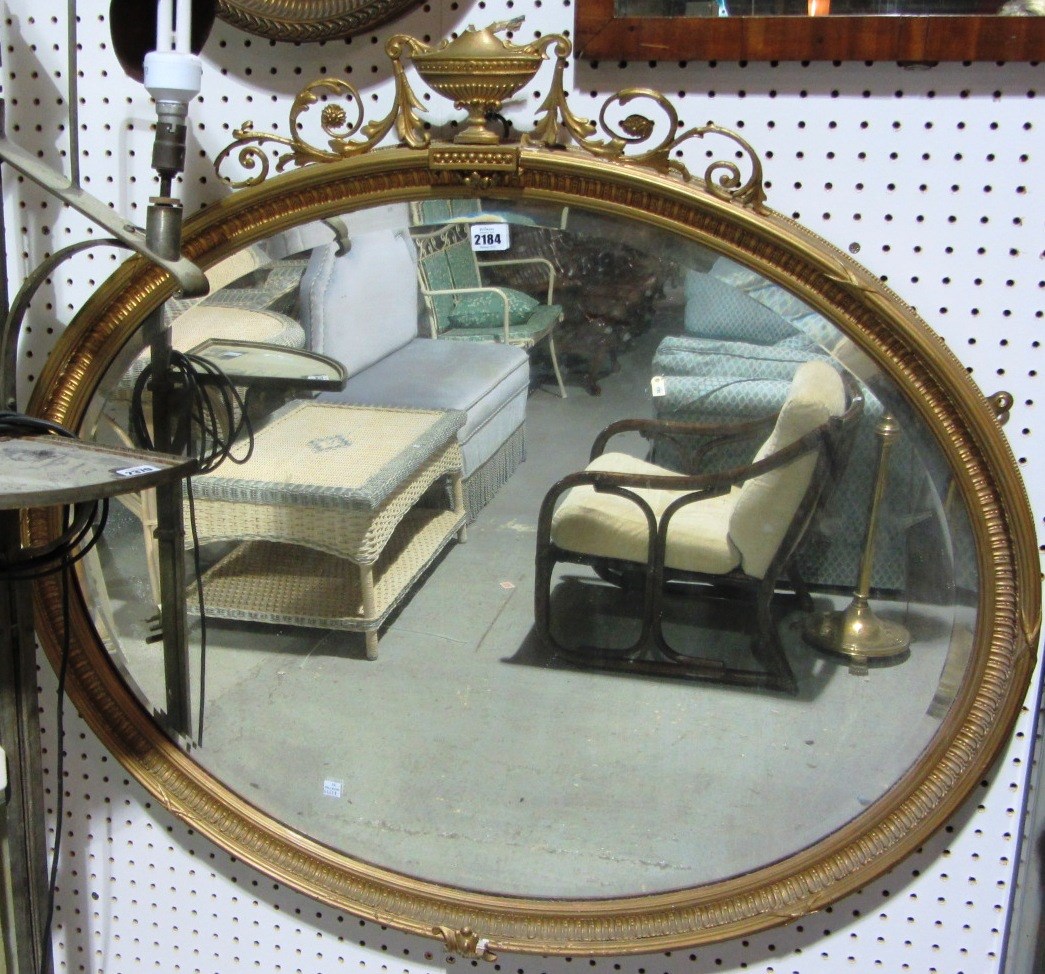 Appraisal: A gilt framed oval wall mirror with urn surmount