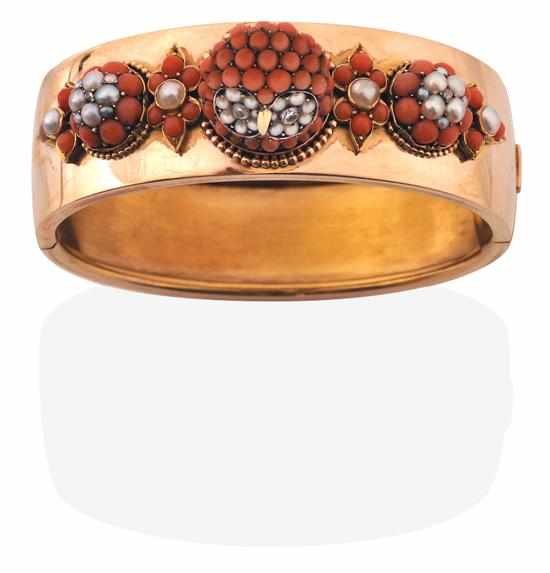 Appraisal: A CORAL SEED PEARL AND DIAMOND BANGLE The wide hinged