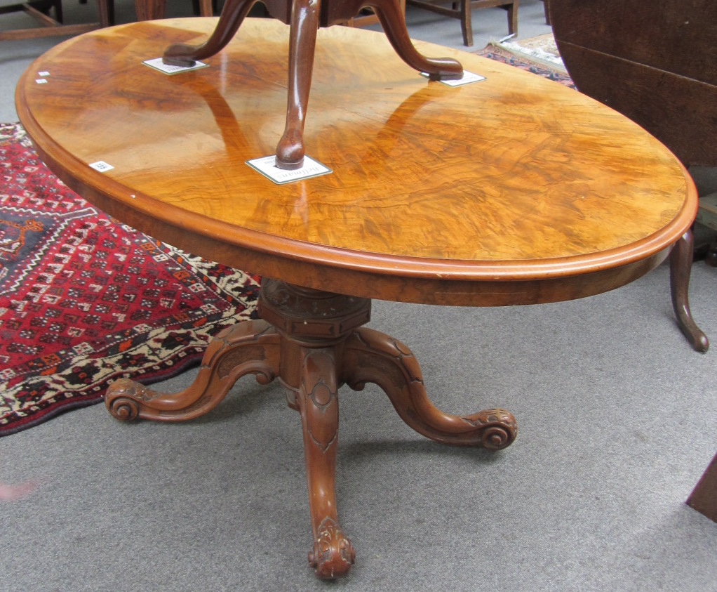 Appraisal: A Victorian figured walnut oval low table on four downswept