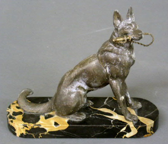 Appraisal: Cast metal German Shepard holding a whip and mounted on